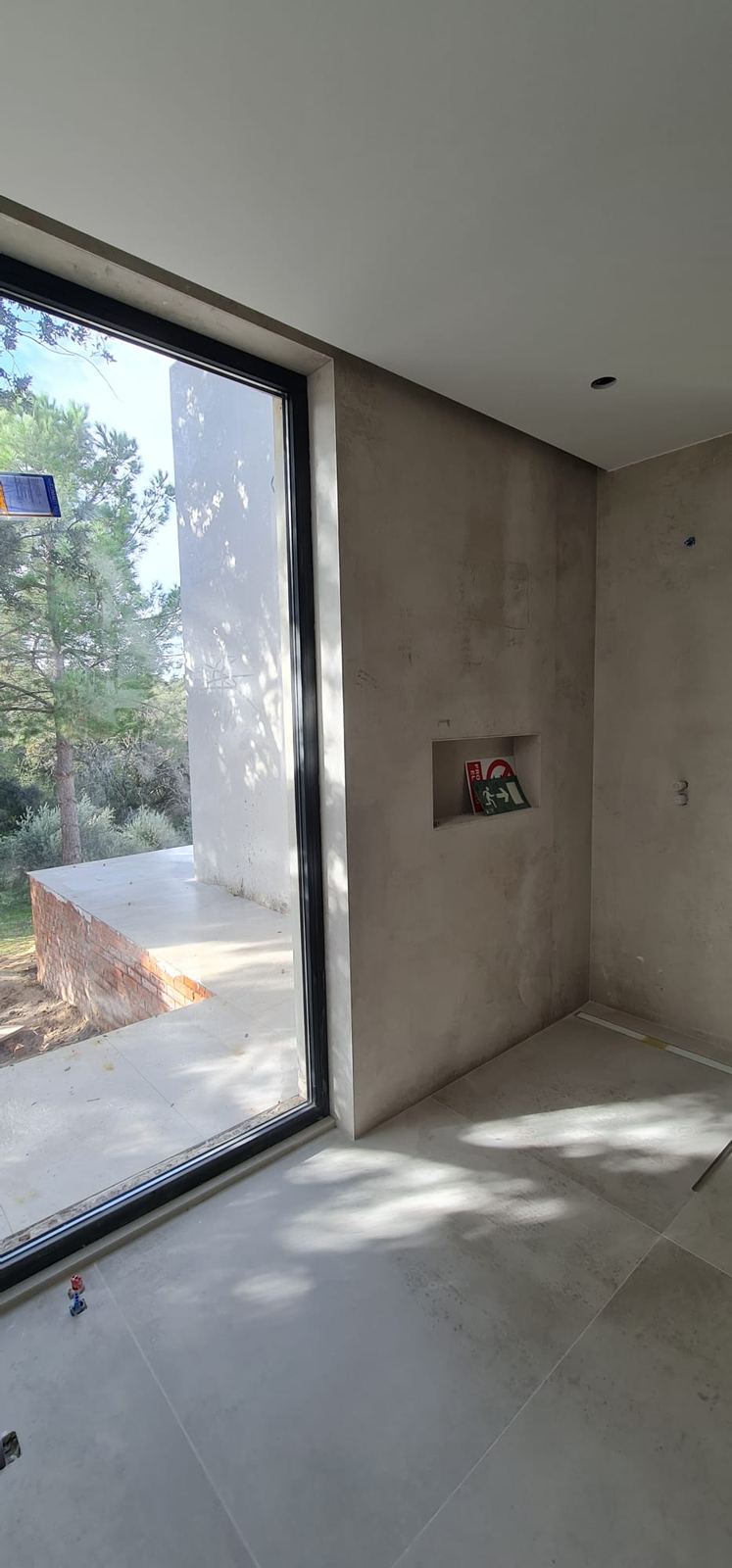 Baño con revestimiento porcelánico y ventanal de suelo a techo, con el techo limpio sin rejillas a la vista.